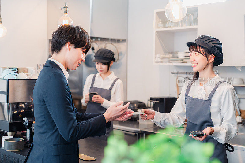 A businessman making a credit card payment at a café